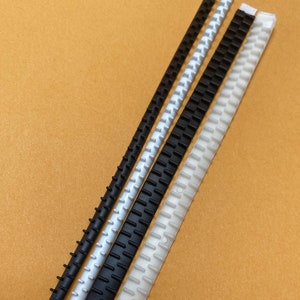 May include: Three plastic binder clips in different sizes. The clips are black and white and have a textured surface.