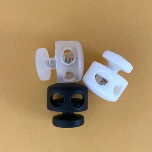 May include: Three toggle clasps, one black, two white. The clasps have a spring mechanism and two holes.