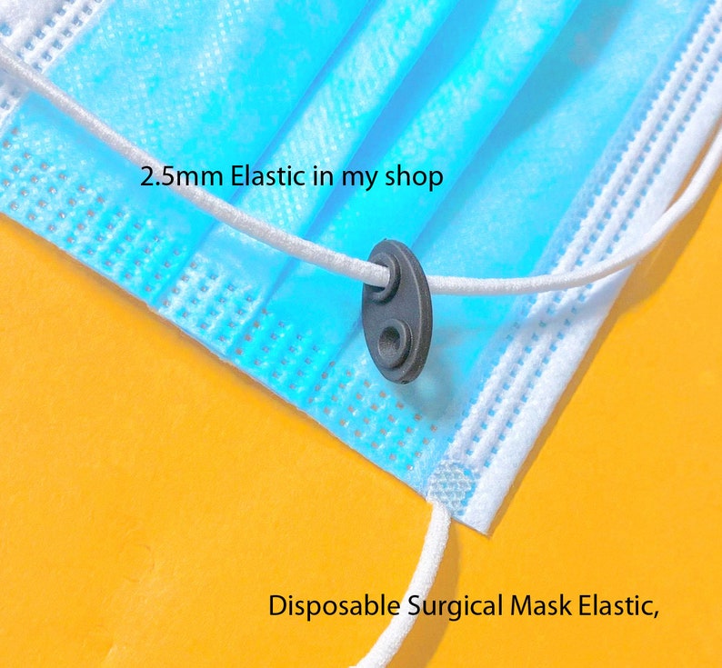 May include: Close-up of a blue disposable surgical mask with white elastic ear loops. The elastic is threaded through a black plastic adjuster. The text "2.5mm Elastic in my shop" is visible.