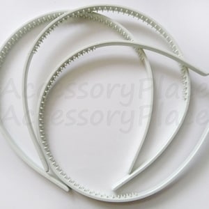 May include: Three white plastic headbands with a textured grip. The headbands are stacked on top of each other.