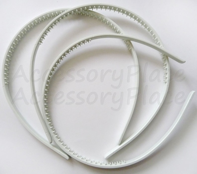 May include: Three white plastic headbands with a textured grip. The headbands are stacked on top of each other.