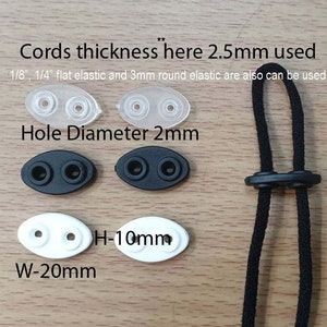 May include: Close-up of two white oval-shaped plastic toggles with two holes each. The toggles are 2 inches wide and 1 inch high. The text "W-20mm" and "H-10mm" is printed below the toggles. Two black oval-shaped plastic toggles with two holes each are shown above the white toggles. The text "Hole Diameter 2mm" is printed above the black toggles. Two clear plastic toggles with two holes each are shown above the black toggles. The text "Cords thickness here 2.5mm used" is printed above the clear toggles. The text "1/8", 1/4" flat elastic and 3mm round elastic are also can be used." is printed below the clear toggles. A black cord with two black toggles is shown on the right side of the image.