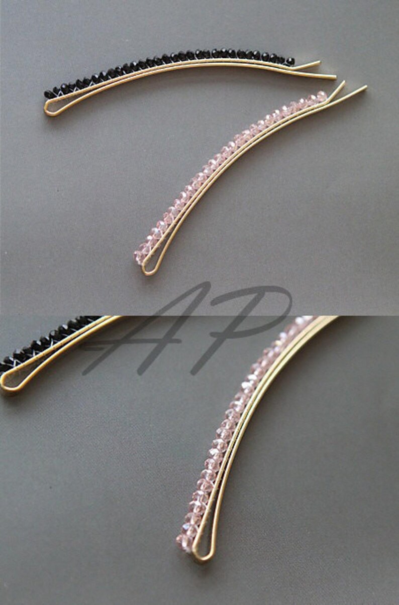 May include: Two gold-toned hair barrettes. One is adorned with black beads, the other with pink beads. The barrettes have a curved design, and the beads are evenly spaced along the top. These hair accessories are suitable for various hairstyles.