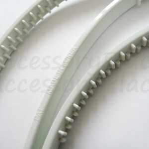 May include: Two white plastic hair bands with a textured grip. The bands are made in Korea and have the text "Made in Korea" printed on them.