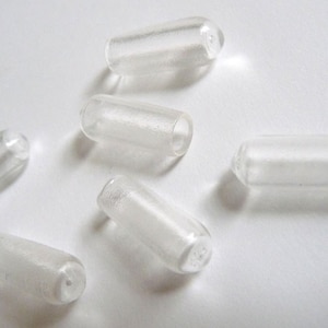 May include: Six clear plastic caps for bottles or containers. The caps are cylindrical and have a small hole at one end.