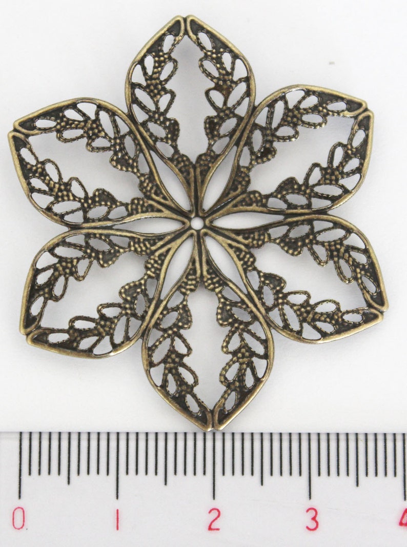 May include: A bronze-colored metal flower charm with a delicate, intricate design. The charm is approximately 2 inches in diameter and has a hole in the center for attaching to jewelry or other crafts.