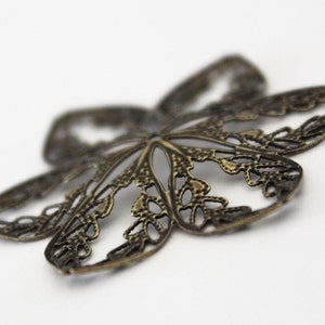 May include: A bronze butterfly-shaped metal charm with a delicate, intricate design. The charm is perfect for adding a touch of whimsy to jewelry or crafts.