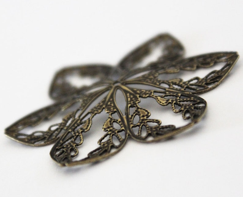 May include: A bronze butterfly-shaped metal charm with a delicate, intricate design. The charm is perfect for adding a touch of whimsy to jewelry or crafts.