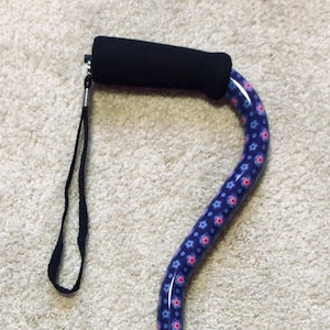 May include: A blue and pink floral patterned walking cane with a black foam handle and a black wrist strap.