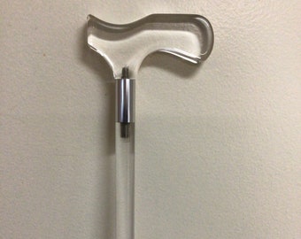 May include: A clear acrylic cane with a silver metal accent at the top of the handle.