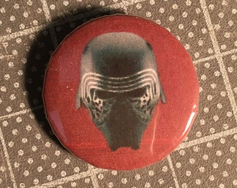 May include: Red button with a black and white image of Kylo Ren's helmet from Star Wars. The button has the text "The Button Depot" and "And Other Goodies" on it.