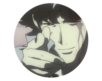 May include: A close-up of a man's face with a smirk. He is looking directly at the viewer with his right hand raised in a gesture of pointing. The background is blurred.