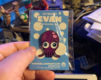 May include: Purple enamel pin of a cartoon octopus with large blue eyes and pink spots. The pin is on a blue background with white polka dots. The text "SAY HELLO TO EVAN AN ENAMEL PIN" is at the top of the card. The text "WWW.YELLOWRANT.COM #EVNAUTILUS TM & © Ben Lee, all rights reserved." is at the bottom of the card.