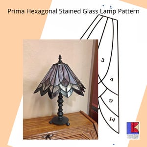 Könnte beinhalten: Eine Tiffany-Lampe mit einem sechseckigen Schirm in Lila- und Silbertönen. Die Lampe steht auf einem Holztisch. Rechts im Bild ist ein Muster für die Lampe abgebildet. Das Muster ist mit den Zahlen 3, 4, 9 und 14 beschriftet.