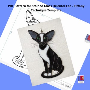 Op de afbeelding: Een zwart-wit gebrandschilderd patroon van een zittende Oosterse kat. Het patroon is genummerd voor de verschillende glasstukken. Het patroon is voor een Tiffany-techniek gebrandschilderd project.