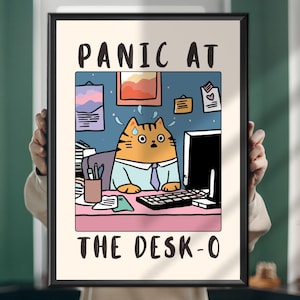 Puede incluir: Impresión artística enmarcada con un gato de dibujos animados en un escritorio, con el texto "PANIC AT THE DESK-O". El gato es naranja, lleva camisa y corbata, con aspecto estresado. El fondo es azul con elementos de oficina.
