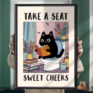 Puede incluir: Un póster enmarcado con un gato negro leyendo un libro en un inodoro. El texto "TAKE A SEAT SWEET CHEEKS" está presente. El fondo muestra un baño con plantas y una ventana, con un estilo de dibujos animados.