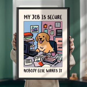 Op de afbeelding: Een ingelijste print met een cartoon gouden hond die aan een bureau zit met een computer, stapels papier en een koffiemok. De tekst bovenaan luidt MY JOB IS SECURE en de tekst onderaan luidt NOBODY ELSE WANTS IT.