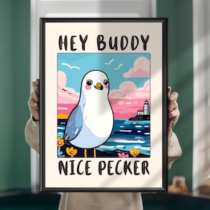 May include: A framed wall art print featuring a cartoon seagull standing by the sea with a lighthouse in the background. The text HEY BUDDY is printed at the top and NICE PECKER is printed at the bottom in bold black capital letters.