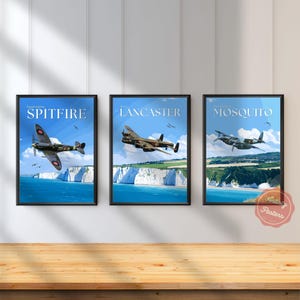 Op de afbeelding: Een set van drie ingelijste posters met historische militaire vliegtuigen. De eerste toont een Supermarine Spitfire, de tweede een Avro Lancaster en de derde een De Havilland Mosquito, vliegend boven witte kliffen en blauw kustwater.