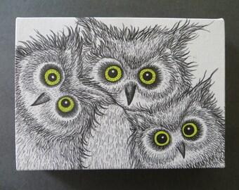 May include: A canvas art piece featuring three stylized owls. The owls are depicted in black and white with detailed feathering and large, bright yellow eyes. The artwork is on a white canvas.