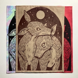 May include: Three fabric panels with deer illustrations. The central panel features two deer under a starry night sky with a full moon, in brown ink on tan fabric. The other panels are black and red with similar deer designs.