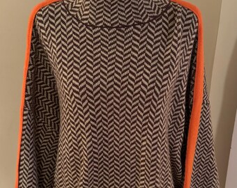 May include: A brown and beige sweater with a herringbone pattern and orange trim on the sleeves.