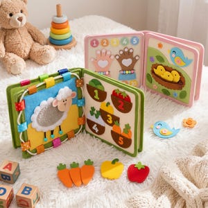 May include: A multi-page felt quiet book featuring interactive elements like a white sheep, numbered vegetable pockets, counting hands, and a bird nest scene. The book includes detachable felt pieces such as carrots, a pepper, and a tomato.