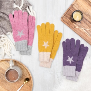 May include: Three pairs of knitted gloves with a star design. The gloves are in pink, yellow, and purple.