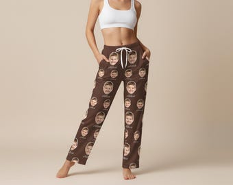 May include: Brown pajama pants featuring a repeating pattern of a child's face and the name "Abbott" in a script font. The pants have a drawstring waist and pockets. The model is wearing a white sports bra.
