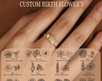 Puede incluir: Un anillo dorado con un grupo de pequeños motivos florales detallados. Sobre el anillo, el texto dice CUSTOM BIRTH FLOWER'S. Debajo, una tabla muestra doce meses con ilustraciones en línea negra de varias flores de nacimiento.