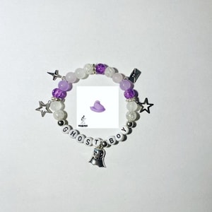 May include: A white and purple beaded bracelet with a ghost charm and the words "GHOST BOY" spelled out in white beads.