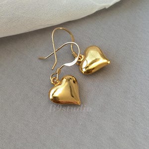 May include: A pair of gold heart-shaped earrings with a simple hook closure.