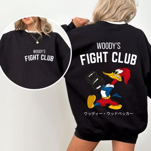 a woman wearing a black sweatshirt with a cartoon character on it
