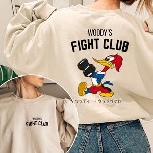 a woman wearing a sweatshirt that says woody's fight club