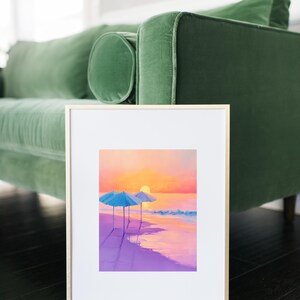 以下が含まれることがあります： 夕暮れのピンク色の砂浜に青い傘が2つあるビーチの風景を描いた額縁付きの絵画。太陽が海に沈み、シーンに温かい光を投げかけています。