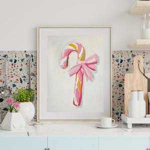 May include: A pink and white candy cane with a pink bow on a white background. The candy cane is painted in a whimsical style.