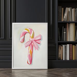 May include: A pink and white striped candy cane with a pink bow. The candy cane is painted in a whimsical style and is set against a white background.