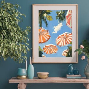 May include: A framed painting of a summer scene with orange and white striped beach umbrellas against a blue sky with palm trees.