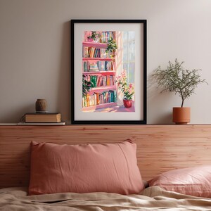 K&ouml;nnte beinhalten: Ein gerahmter Kunstdruck zeigt eine gem&uuml;tliche Innenszene. Ein rosa B&uuml;cherregal mit bunten B&uuml;chern steht in der N&auml;he eines Fensters mit Sonnenschein. Topfpflanzen und Blumen verleihen dem Raum eine nat&uuml;rliche Note. Das Kunstwerk ist in einem schwarzen Rahmen.