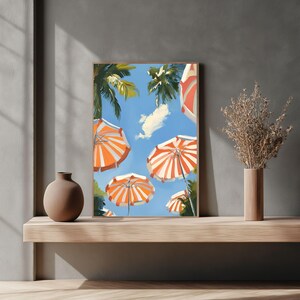 May include: A framed illustration of a beach scene with orange and white striped umbrellas against a blue sky with white clouds. The umbrellas are arranged in a semi-circle, with the tops of the umbrellas facing the viewer.