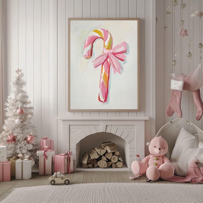 May include: A pink and white candy cane with a pink bow, painted on a white canvas, hanging on a white wall in a room with a fireplace and a white Christmas tree.