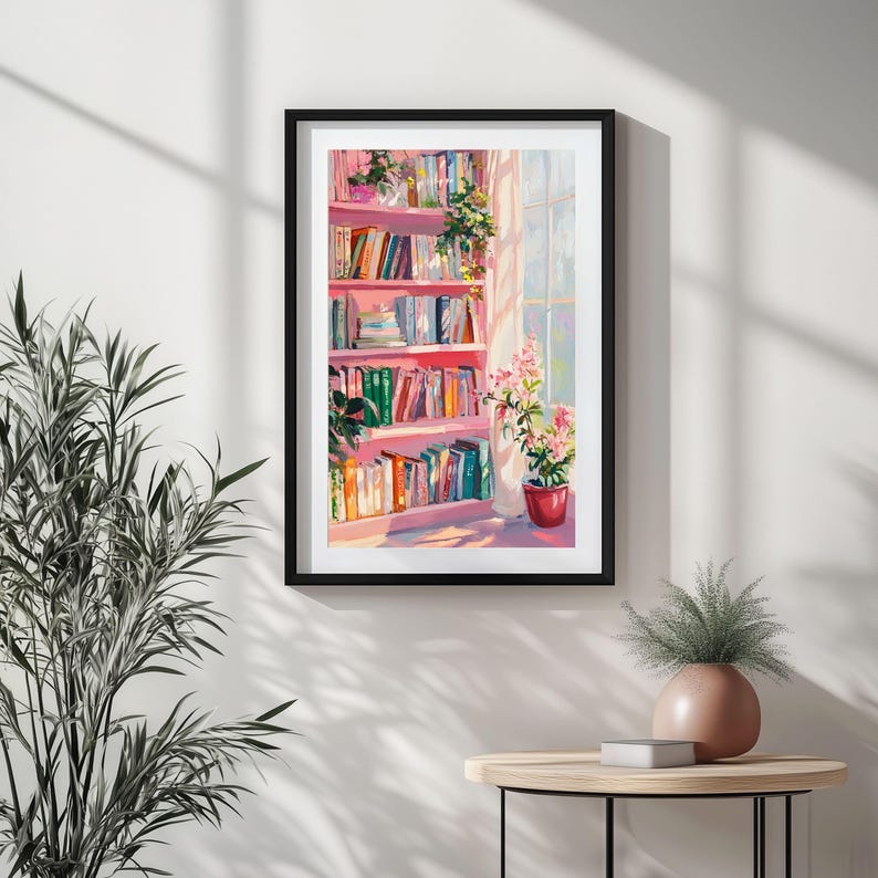K&ouml;nnte beinhalten: Gerahmter Kunstdruck, der ein rosa B&uuml;cherregal voller B&uuml;cher zeigt. Das Kunstwerk zeigt ein Fenster mit Sonneneinstrahlung, das die B&uuml;cher und Pflanzen beleuchtet. Ein roter Topf mit rosa Blumen steht auf dem Boden. Der Druck ist in einem schwarzen Rahmen.