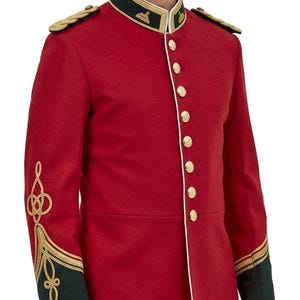 May include: A bright red military-style tunic featuring a high dark green collar, gold-toned buttons, and gold braided embroidery on the shoulders and cuffs. The jacket includes white piping along the front closure and dark green sleeve cuffs.