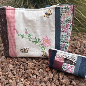 May include: A white tote bag and matching pencil case with floral and butterfly embroidery. The tote bag has a patchwork design with pink gingham, floral, and denim panels. The pencil case has a similar patchwork design with lace trim.