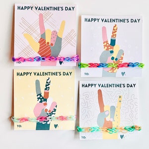 Könnte beinhalten: Vier bunte Valentinstagskarten mit Handgesten und dem Text "Happy Valentine's Day". Jede Karte hat ein Gummiband-Armband.