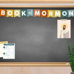 Könnte beinhalten: Eine Tafel mit den Worten "BOOK of MORMON" in weißen Buchstaben auf einem Banner darüber. Auf der Tafel befindet sich ein Bild von Jesus Christus und zwei Blätter Papier mit den Worten "WELCOME TO PRIMARY" darauf. Auf der rechten Seite der Tafel steht eine grüne Pflanze in einem Topf.