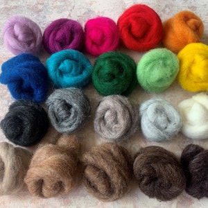 May include: Twenty-four balls of wool in various colors, including purple, pink, red, orange, yellow, green, blue, gray, brown, and white. The balls are arranged in rows on a light gray surface.