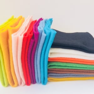May include: A stack of felt squares in various colors, including green, orange, white, black, brown, yellow, blue, red, pink, and light green.