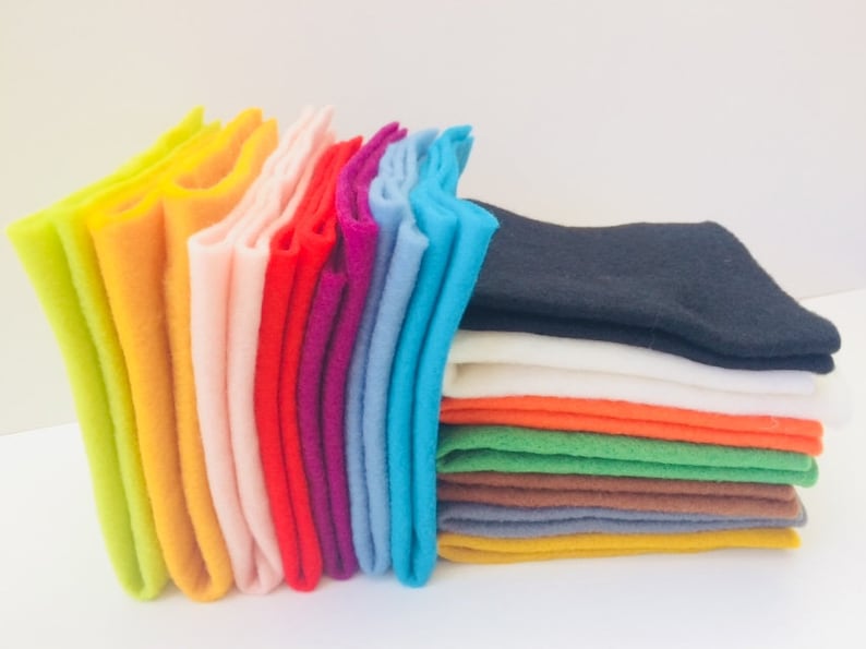 May include: A stack of felt squares in various colors, including green, orange, white, black, brown, yellow, blue, red, pink, and light green.